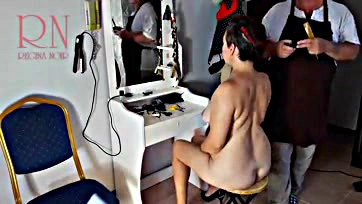 A topless woman gets a haircut in a barbershop