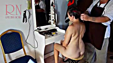 A topless woman gets a haircut in a barbershop