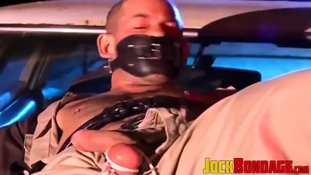 Submissive police officer tied up on the hood of a car