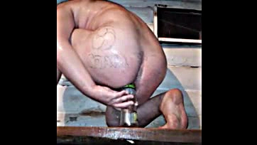 He wanks while seated, barebacking a beer bottle